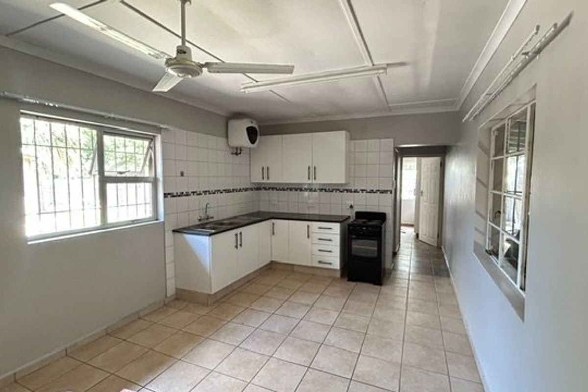 A functional kitchen featuring white cabinetry, tiled backsplash, ceramic flooring, and a freestanding stove, offering a clean and practical layout for renovation.