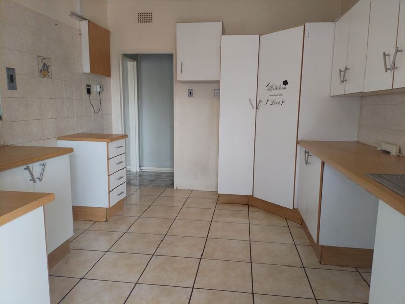 A functional kitchen space featuring tiled flooring, laminate countertops, and ample built-in cabinetry, ready for a modern update.