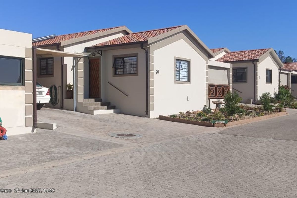 Front view of a residential property featuring a paved driveway, tiled roof, and aluminium window frames in a well-maintained estate setting.