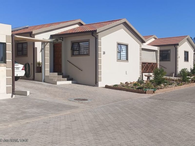 Front view of a residential property featuring a paved driveway, tiled roof, and aluminium window frames in a well-maintained estate setting.