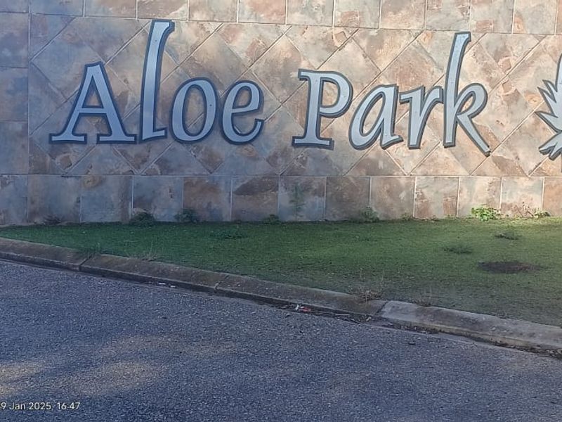 Entrance signage for Aloe Park residential estate featuring stone cladding and paved driveway access.