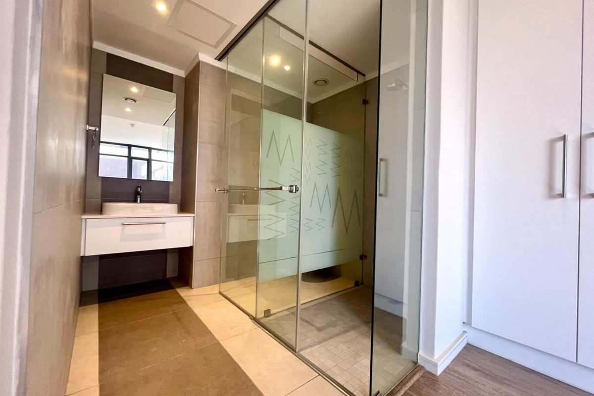 Modern bathroom featuring a glass-enclosed shower, wall-mounted vanity with vessel sink, and neutral tile finishes.