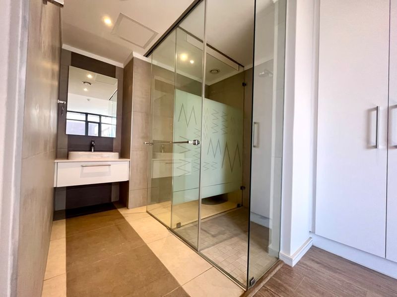 Modern bathroom featuring a glass-enclosed shower, wall-mounted vanity with vessel sink, and neutral tile finishes.