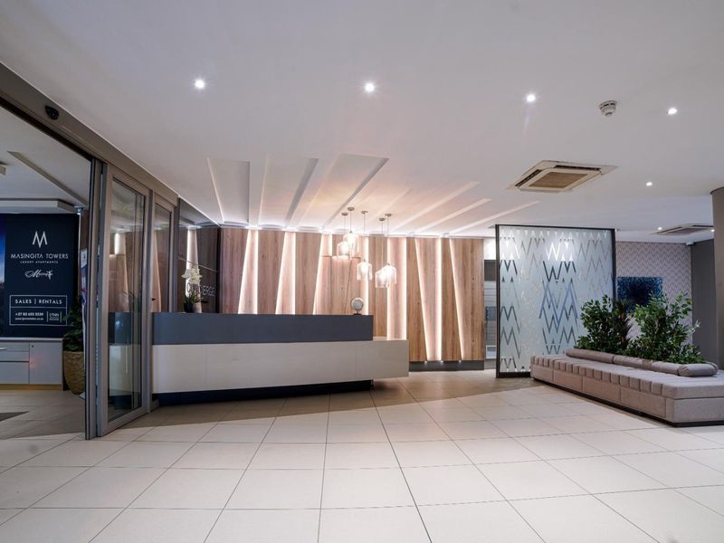 Modern apartment building concierge reception area featuring sleek cabinetry, decorative wood paneling, and high-quality tiled flooring.