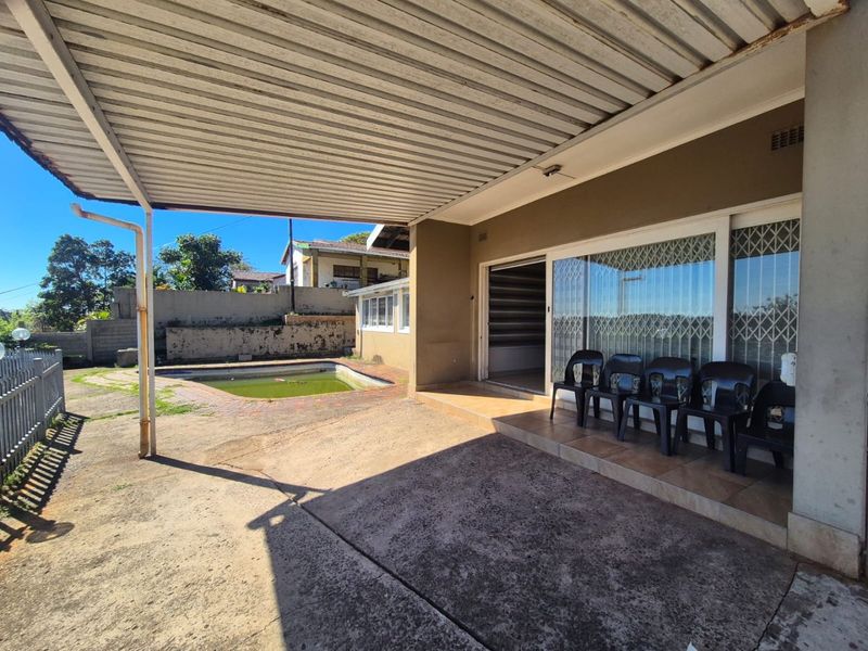 Covered patio area overlooking a swimming pool, featuring sliding glass doors with security gates and direct access to the outdoor space.
