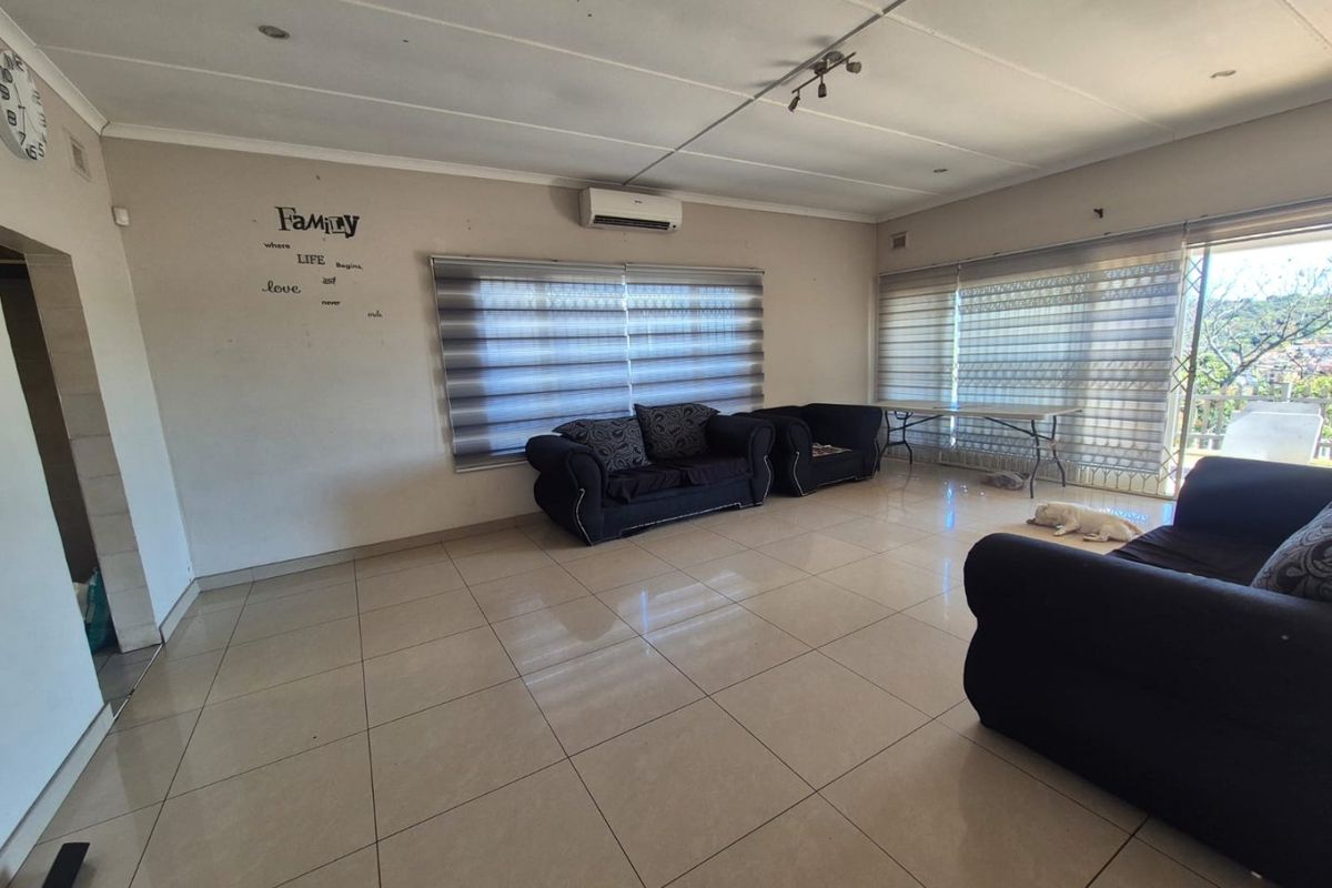 Spacious living room featuring neutral tiled flooring, a wall-mounted air conditioning unit, and large windows with modern roller blinds.