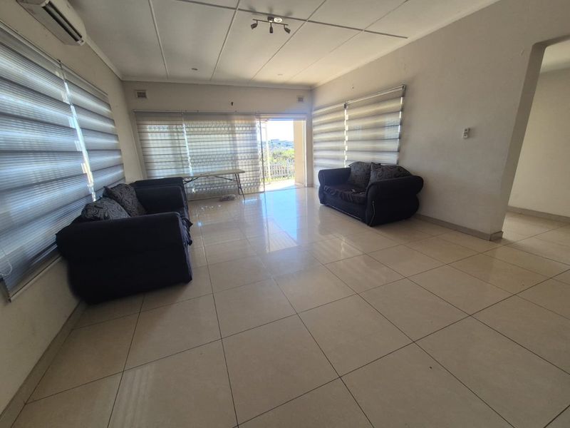 Spacious living room featuring large format floor tiles, split-system air conditioning, and sliding glass doors leading to an outdoor area.