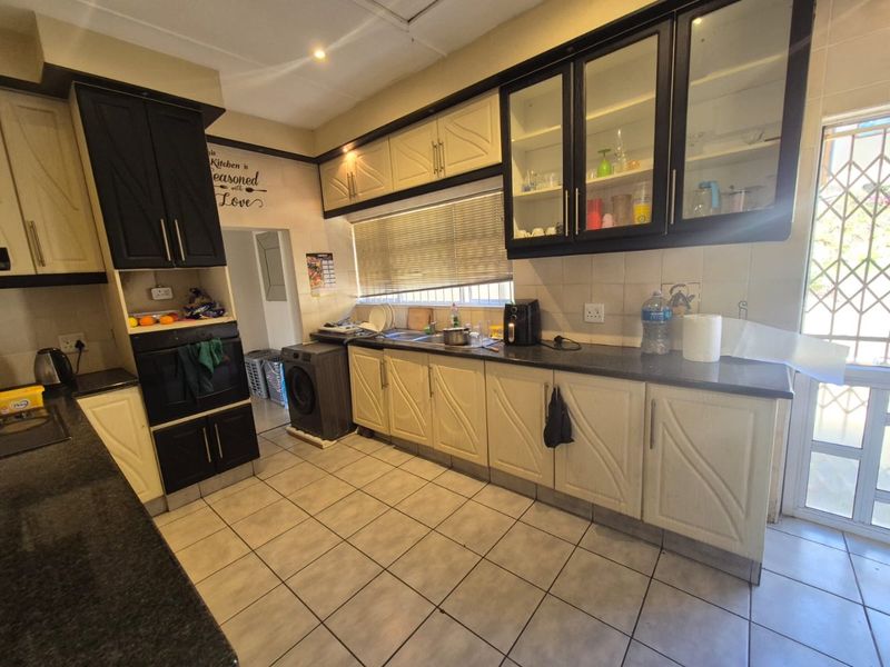 Functional kitchen featuring dark and light contrast cabinetry, granite countertops, built-in oven, and tiled flooring with direct access to an exterior door.