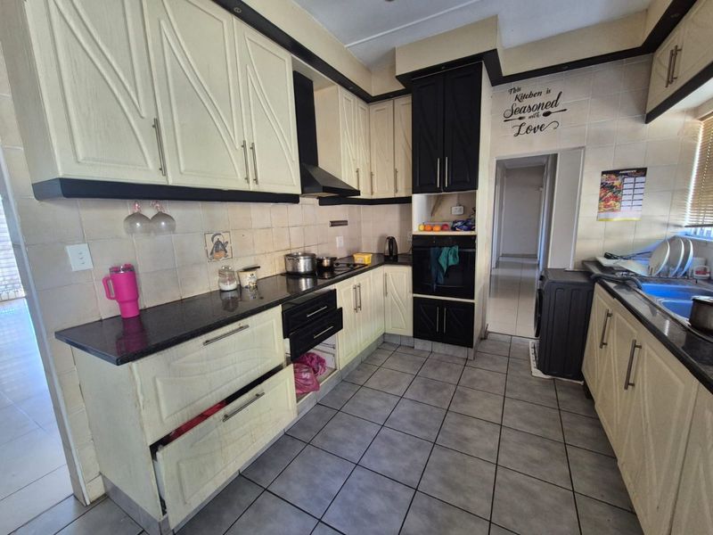 A functional kitchen featuring two-tone cabinetry, granite countertops, built-in oven, and extractor fan with tiled flooring and backsplash.
