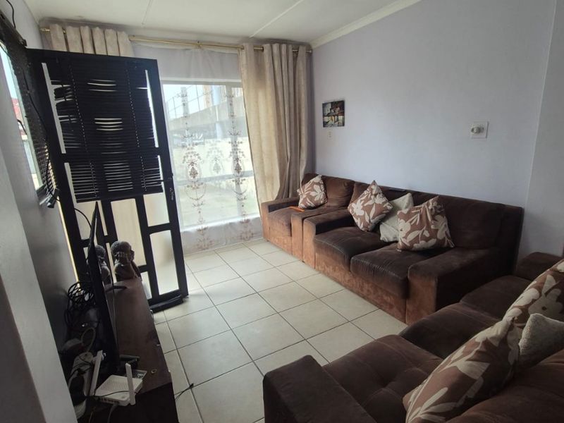 A functional living room featuring tiled flooring and a large window, providing natural light to the space.