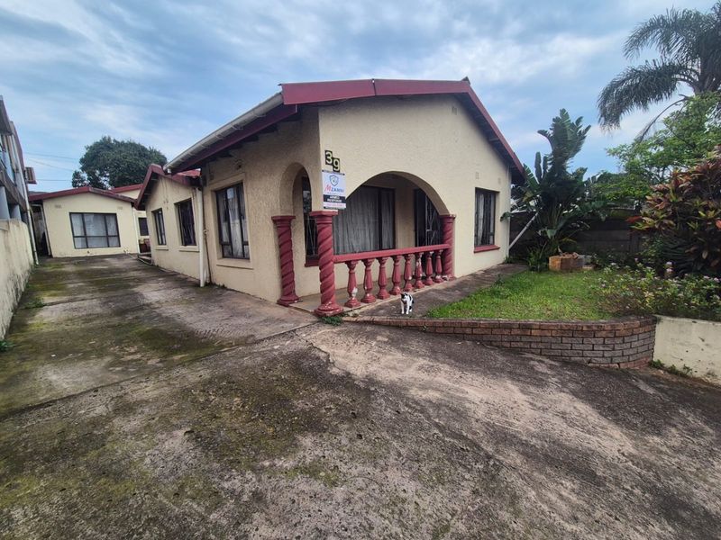 Front view of a single-story house featuring a covered porch with decorative columns, a concrete driveway, and a small front garden area.