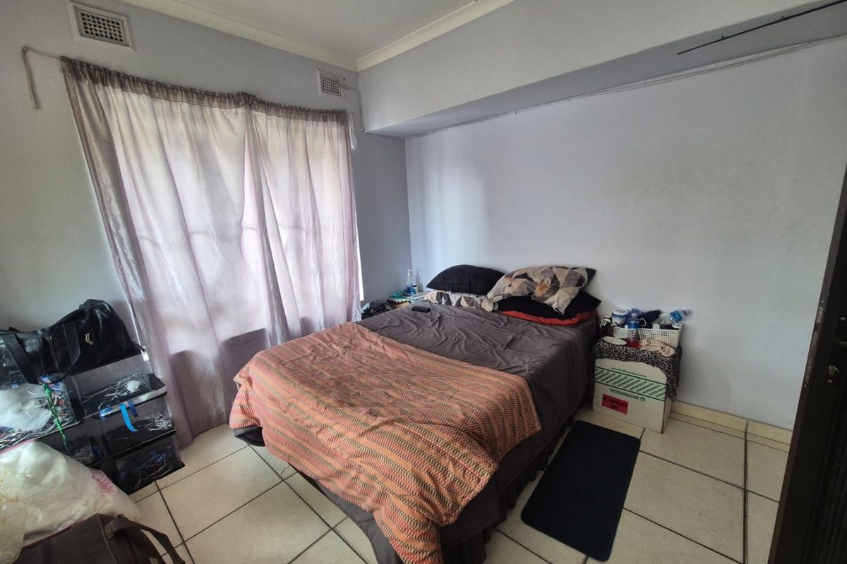 A bedroom featuring tiled flooring and ceiling ventilation, providing a functional space with neutral wall finishes.