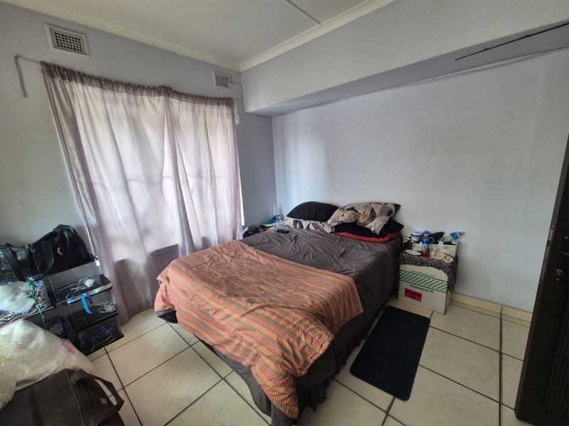 A bedroom featuring tiled flooring and ceiling ventilation, providing a functional space with neutral wall finishes.