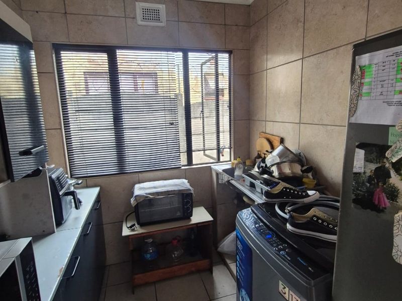 A functional laundry area featuring tiled walls, tiled flooring, and a built-in sink with space for laundry appliances.