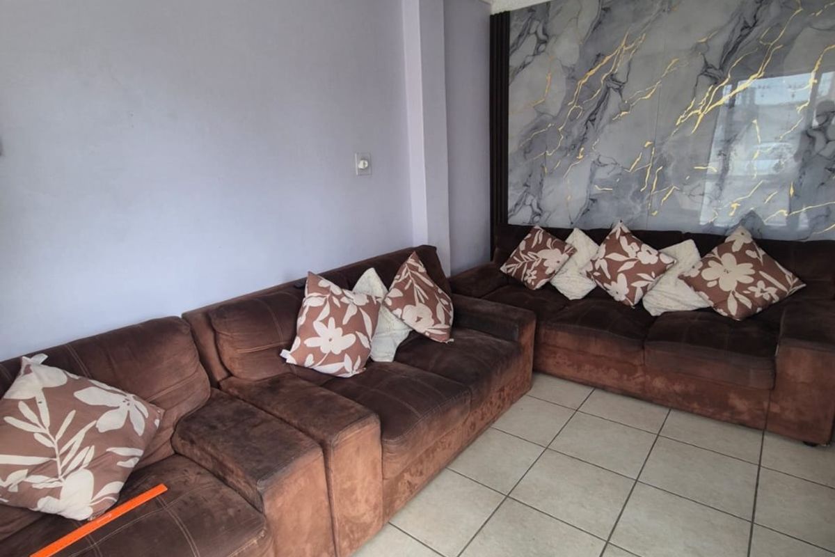 Living room featuring ceramic floor tiles, a decorative marble-effect feature wall, and coved ceiling cornicing.