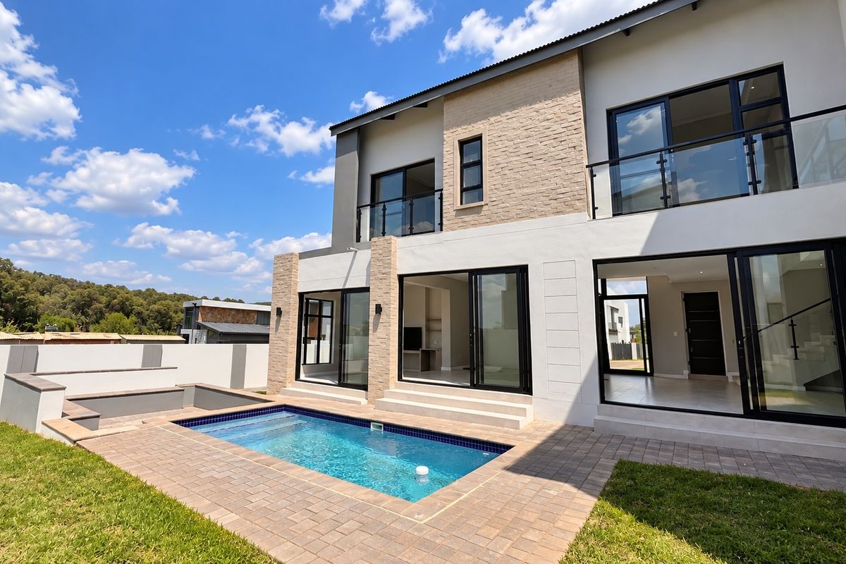 Modern double-story residence featuring a rear patio, swimming pool, stone-clad facade, and large glass sliding doors opening to the interior living spaces.