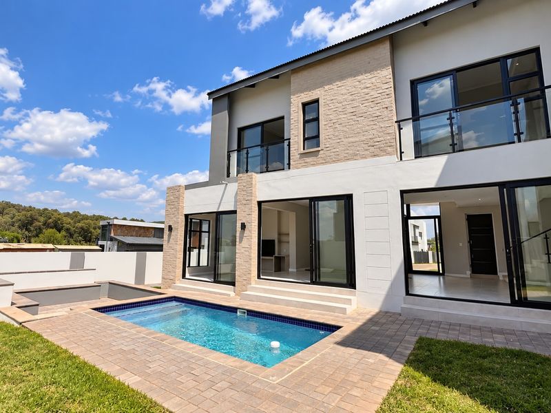 Modern double-story residence featuring a rear patio, swimming pool, stone-clad facade, and large glass sliding doors opening to the interior living spaces.
