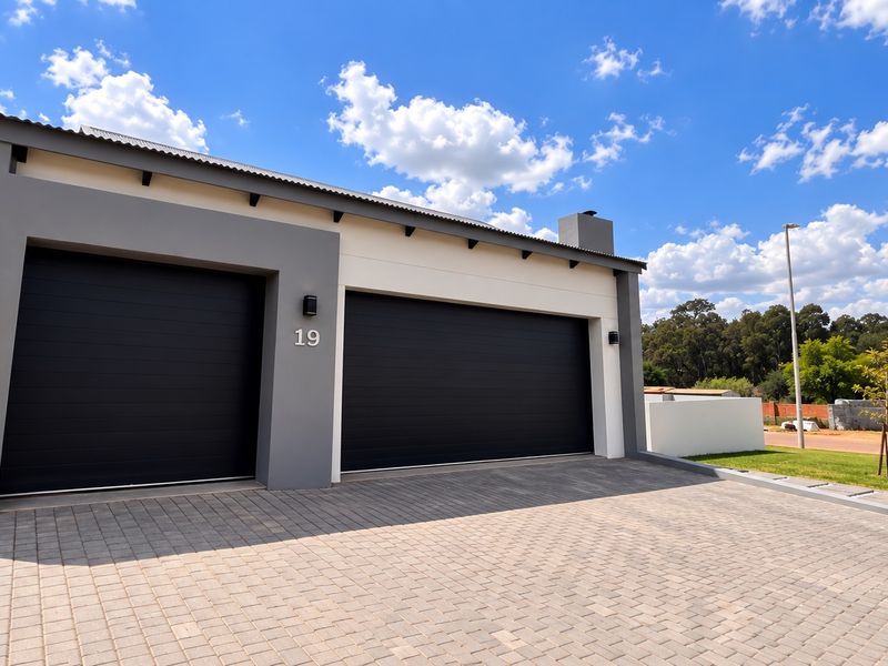 Modern double garage facade with a paved driveway and contemporary grey and white exterior finish.