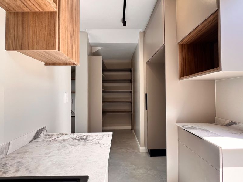A modern, minimalist scullery featuring sleek built-in cabinetry, marble-look stone countertops, and extensive open shelving for organized storage.