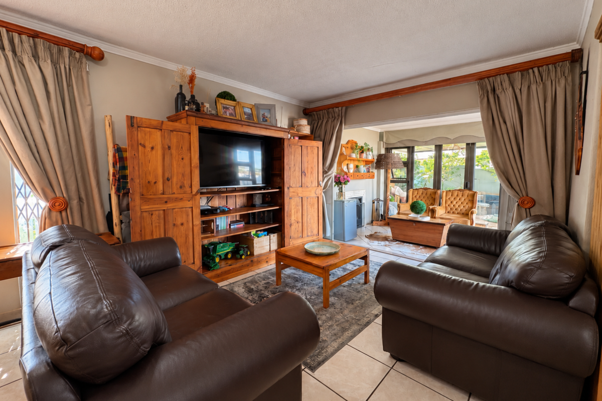 A comfortable living room featuring tiled flooring, coved ceilings, and large sliding glass doors that provide natural light and access to the outdoor area.