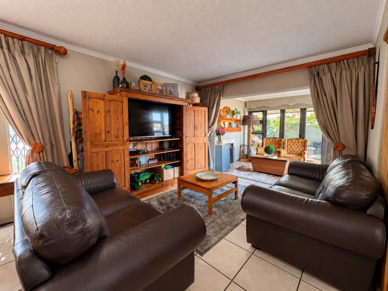 A comfortable living room featuring tiled flooring, coved ceilings, and large sliding glass doors that provide natural light and access to the outdoor area.