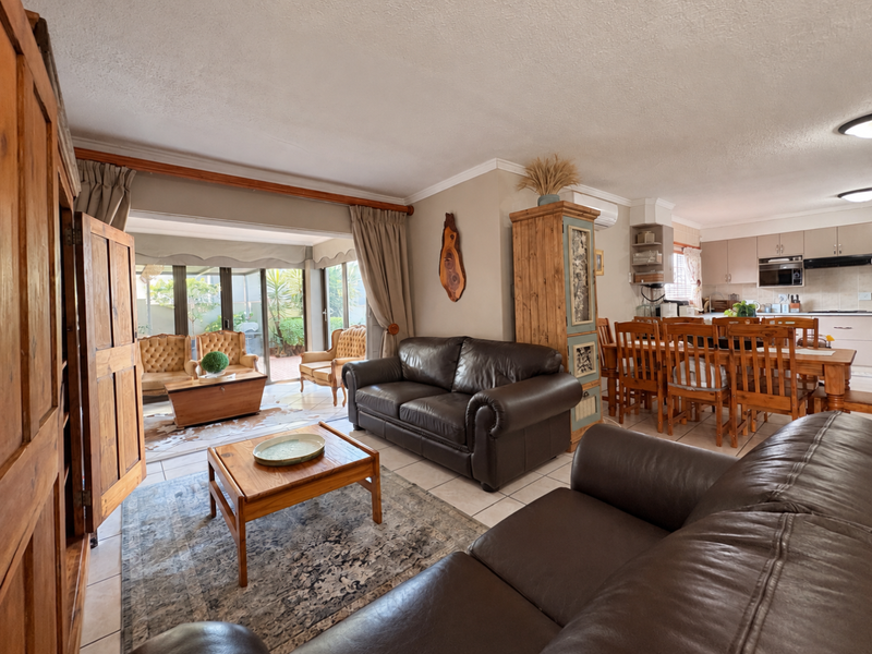Spacious open-plan living and dining area featuring tiled floors, integrated kitchen cabinetry, and large sliding doors providing access to an enclosed patio.