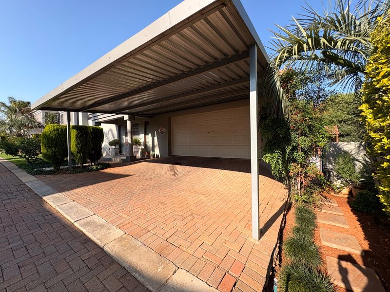 A well-maintained exterior view featuring a paved driveway, a covered carport, and a secure sectional garage door.
