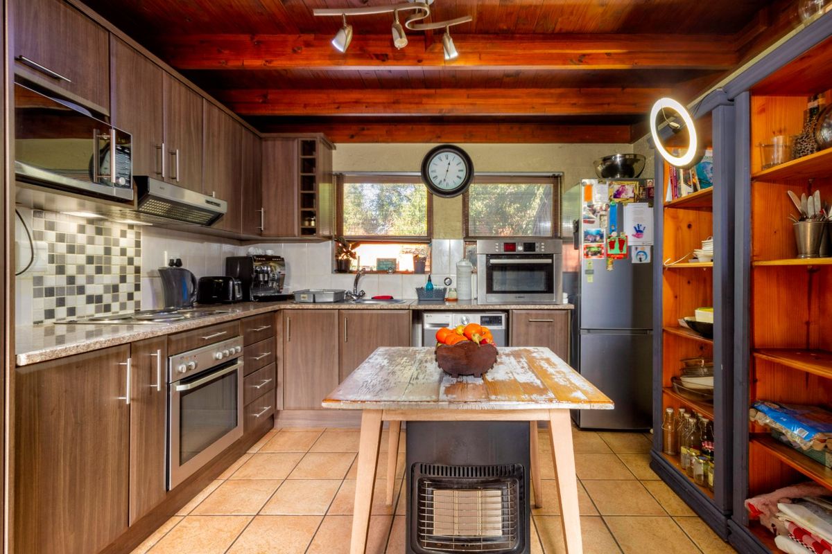 A functional kitchen featuring wood-toned cabinetry, granite countertops, a mosaic backsplash, and exposed timber ceiling beams, providing a warm and practical cooking space.