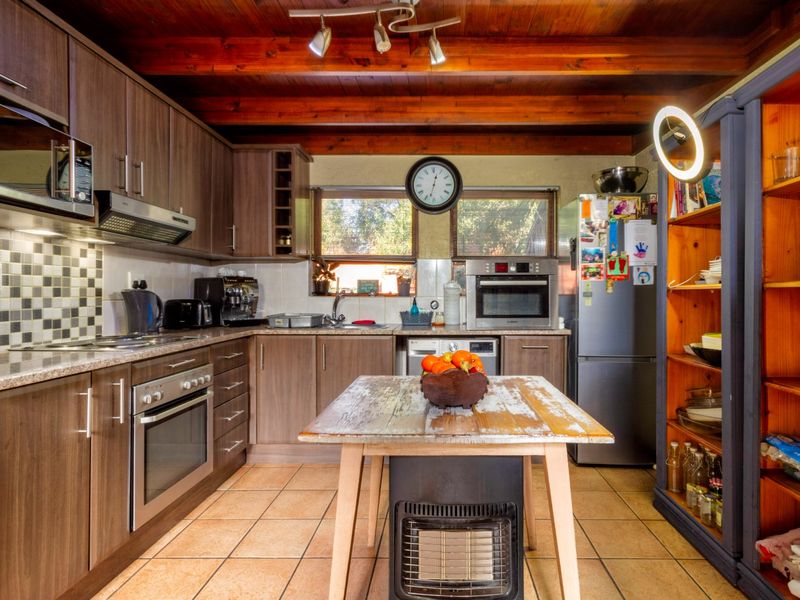 A functional kitchen featuring wood-toned cabinetry, granite countertops, a mosaic backsplash, and exposed timber ceiling beams, providing a warm and practical cooking space.
