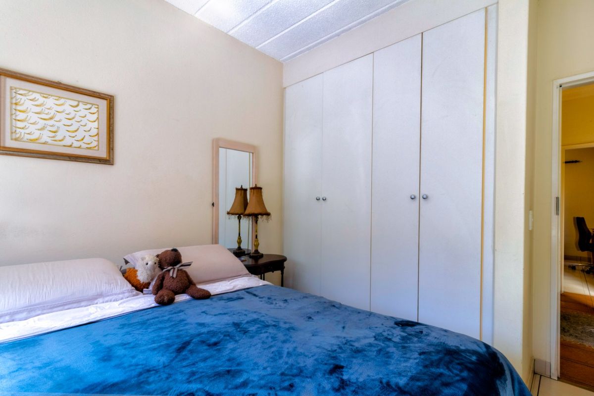 A bedroom featuring a built-in wardrobe with white doors and a textured ceiling, offering functional storage space.