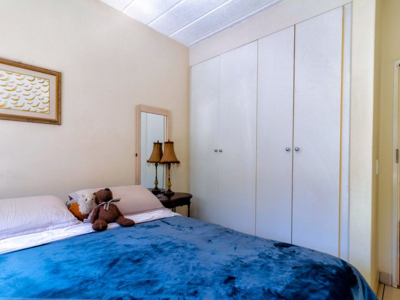 A bedroom featuring a built-in wardrobe with white doors and a textured ceiling, offering functional storage space.