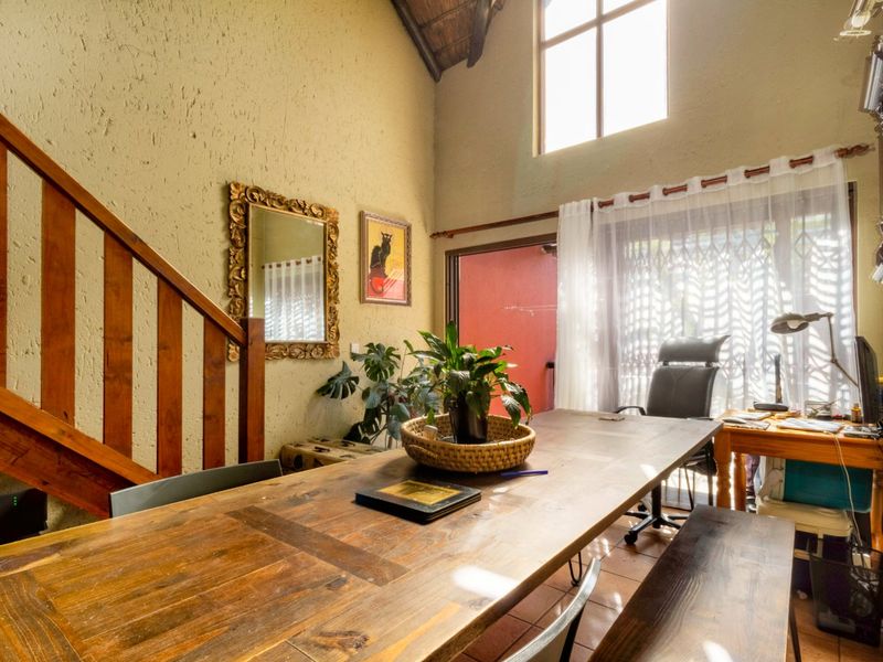 Spacious living area featuring a high vaulted ceiling, timber staircase, tiled flooring, and large windows providing ample natural light.