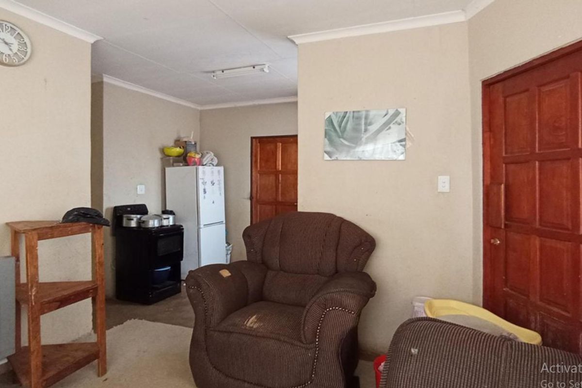 A living area featuring a timber panelled door and coved ceilings, requiring cosmetic updates to improve the overall aesthetic and condition of the space.