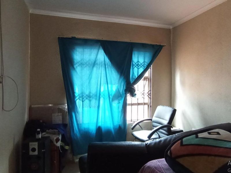 A bedroom featuring a window with security bars and coving, currently requiring cosmetic updates to the wall finishes.