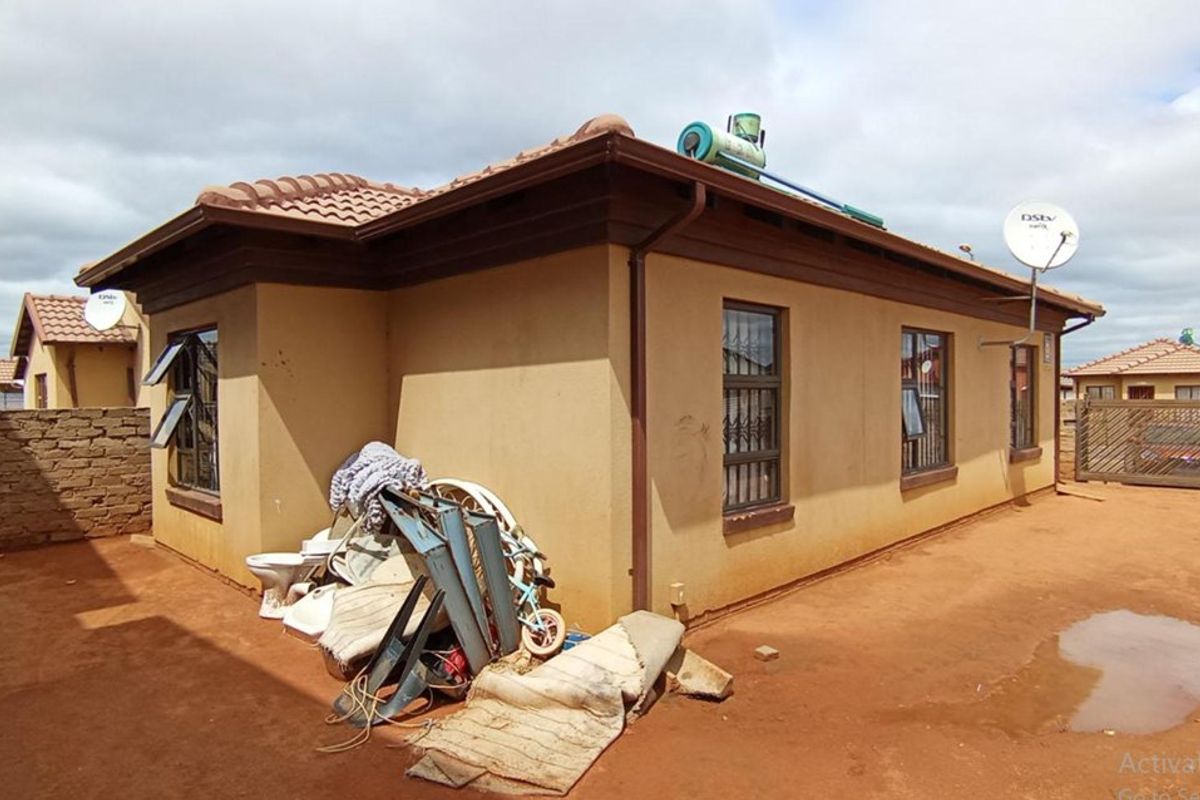 Rear exterior view of the house featuring a tiled roof, solar water heater, and security bars on the windows.
