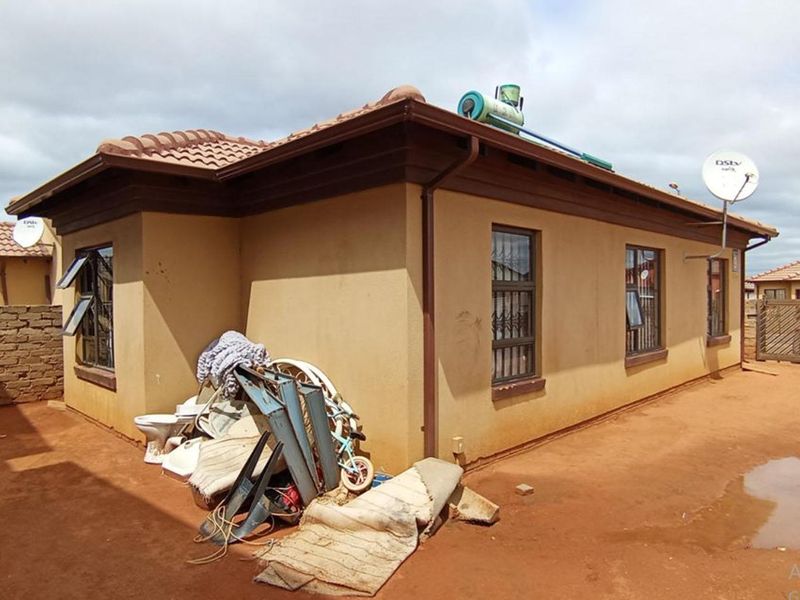 Rear exterior view of the house featuring a tiled roof, solar water heater, and security bars on the windows.
