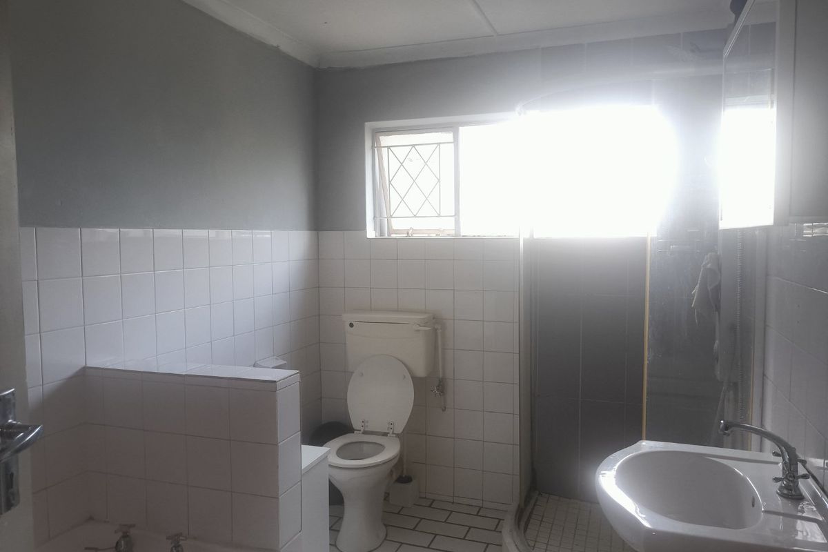 A functional bathroom featuring a bathtub, separate shower enclosure, pedestal basin, and toilet with tiled finishes throughout.