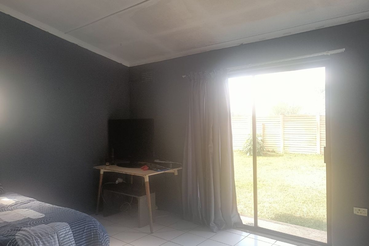 A bedroom featuring tiled flooring and a sliding glass door providing direct access to the rear garden area.