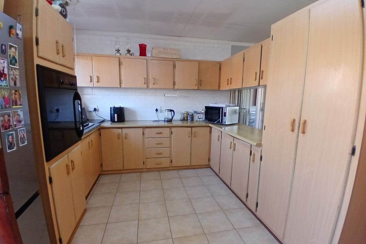 A functional kitchen featuring extensive light wood cabinetry, tiled flooring, a built-in oven, and ample counter space, offering a classic layout ready for modernization.