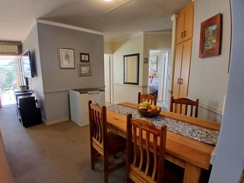 Dining area featuring built-in cabinetry, neutral wall finishes, and access to an adjacent living space and hallway.