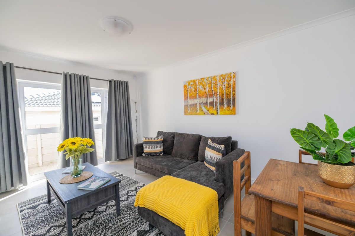 A bright and well-maintained living area featuring tiled flooring, coved ceilings, and a large sliding glass door providing access to the exterior.