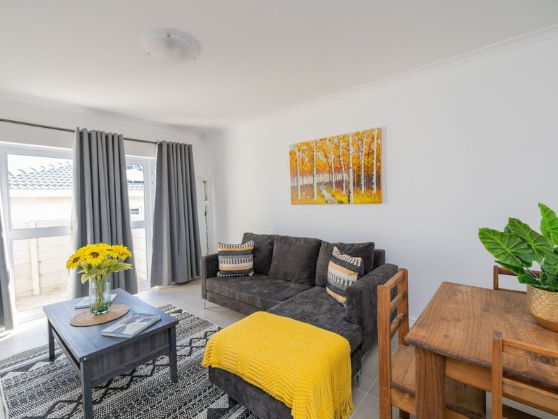 A bright and well-maintained living area featuring tiled flooring, coved ceilings, and a large sliding glass door providing access to the exterior.