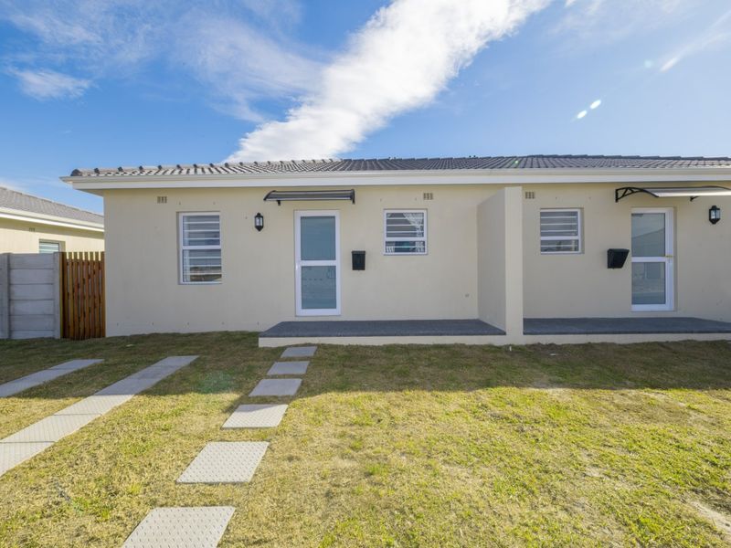 Front elevation of a modern residential unit featuring a tiled roof, paved walkway, and low-maintenance exterior finishes with a small front lawn.