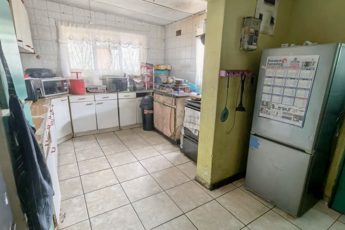 A dated kitchen featuring tiled flooring, built-in cabinetry, and tiled splashbacks, requiring significant cosmetic updates and maintenance to improve its overall condition.