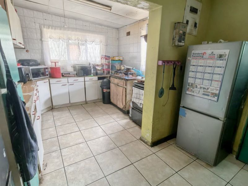 A dated kitchen featuring tiled flooring, built-in cabinetry, and tiled splashbacks, requiring significant cosmetic updates and maintenance to improve its overall condition.