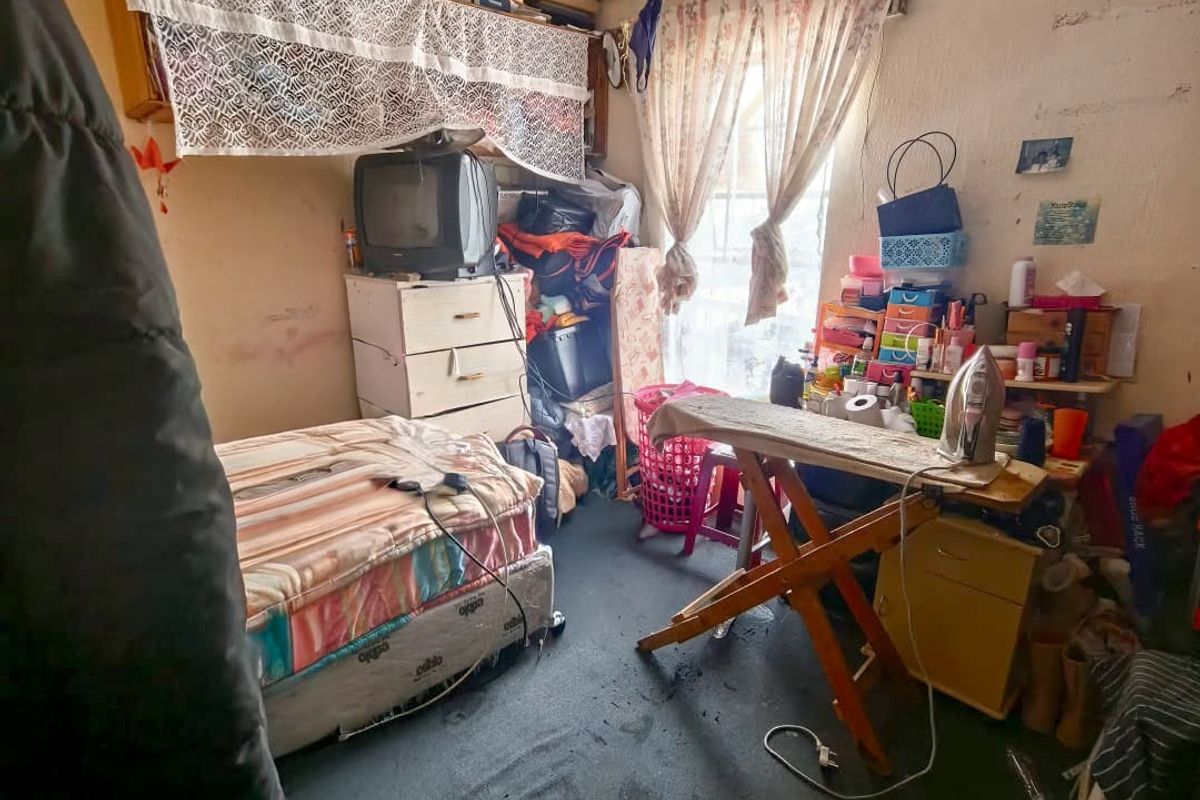 A bedroom space requiring significant maintenance and refurbishment to address wall, ceiling, and flooring condition.