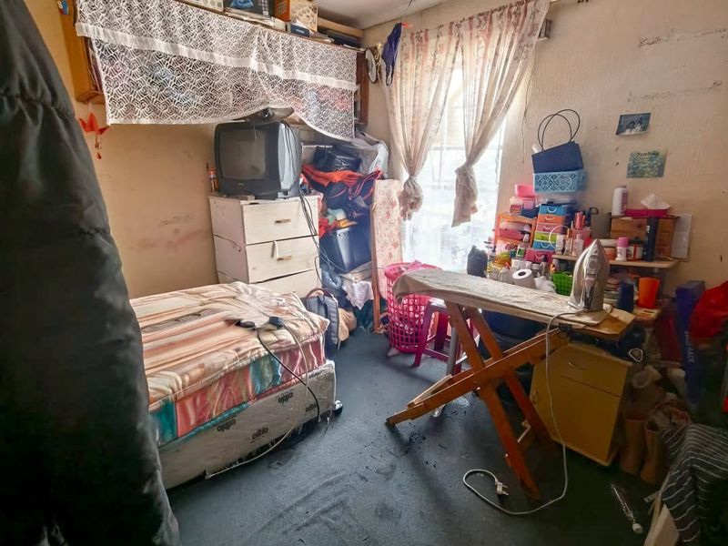 A bedroom space requiring significant maintenance and refurbishment to address wall, ceiling, and flooring condition.
