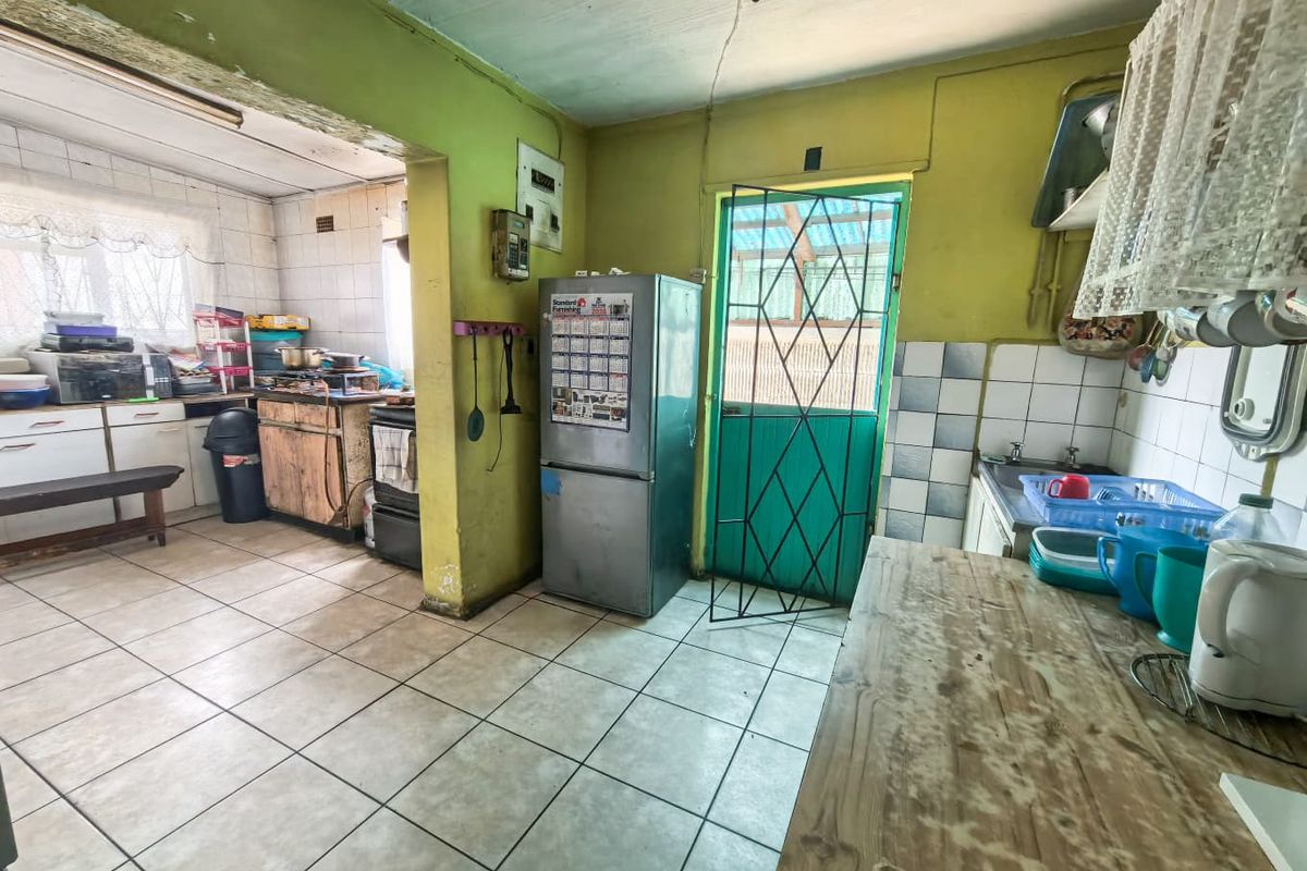 A dated kitchen featuring tiled flooring, built-in cabinetry, and a tiled backsplash, requiring cosmetic updates to modernize the space.