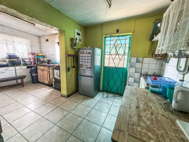 A dated kitchen featuring tiled flooring, built-in cabinetry, and a tiled backsplash, requiring cosmetic updates to modernize the space.