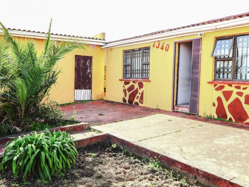 Rear exterior view of the property featuring a concrete patio area, security gates on windows and doors, and a tiled roof structure.